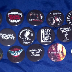May include: A collection of 12 black and white round buttons with various band logos and designs. The buttons feature bands such as My Chemical Romance, MCR, and Thank You For The Venom.