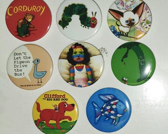 May include: A collection of eight circular pin-back buttons featuring illustrations from children's books, including Corduroy, The Very Hungry Caterpillar, a Siamese cat, Don't Let the Pigeon Drive the Bus, a rainbow-colored child, The Giving Tree, Clifford the Big Red Dog, and a Rainbow Fish.