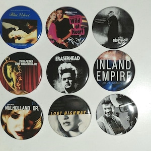 May include: A collection of nine circular pin-back badges featuring film posters and imagery from David Lynch movies, including Blue Velvet, Wild at Heart, The Elephant Man, Twin Peaks, Eraserhead, Inland Empire, Mulholland Dr., and Lost Highway.