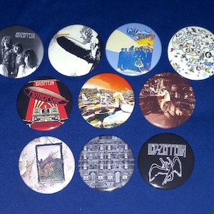Puede incluir: Una colección de diez botones redondos de Led Zeppelin. Los botones presentan varias portadas de álbumes y logotipos de la banda en colores como negro, blanco, rojo y azul. Algunos botones muestran a los miembros de la banda, otros imágenes icónicas.