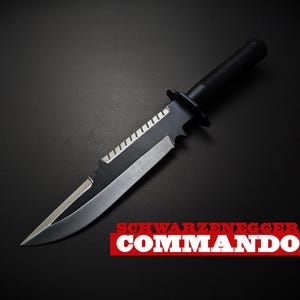 May include: A black and silver commando knife with a serrated edge and a black handle. The text "SCHWARZENEGGER COMMANDO" is displayed in white letters on a red rectangle.