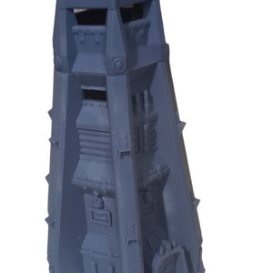 Puede incluir: Una estructura gris en forma de fortaleza con un diseño de varios niveles. El modelo presenta una torre con almenas, ventanas y una fachada detallada. Las púas sobresalen de los lados, lo que aumenta su apariencia imponente. La estructura tiene una puerta.