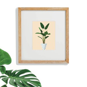 May include: A framed print of a green plant in a blue and white checkered pot on a peach background.