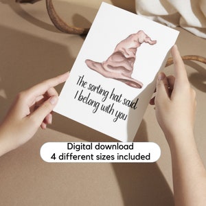 May include: A white card featuring a watercolor illustration of a sorting hat in shades of brown. The text "The sorting hat said I belong with you" is written below the hat in black. The card also includes the text "Digital download 4 different sizes included."