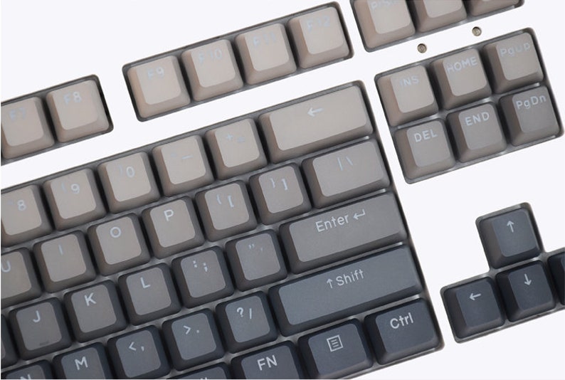 K&ouml;nnte beinhalten: Nahaufnahme einer mechanischen Tastatur mit grauen Tastenkappen. Die Tasten sind in einem Standard-Layout angeordnet, mit alphanumerischen Tasten, Funktionstasten und Pfeiltasten. Die Tastenkappen haben ein Farbverlauf, der von hellgrau zu dunkelgrau &uuml;bergeht.