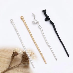 Pode incluir: Quatro grampos de cabelo de metal em prata, dourado, prata e preto. Os grampos prateados e dourados têm uma superfície texturizada. O grampo preto tem um design curvo único. Os acessórios de cabelo são exibidos em uma superfície branca.