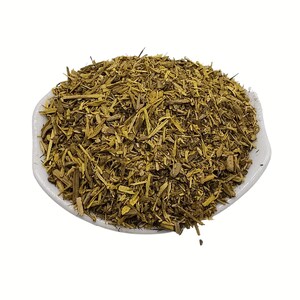 May include: A white, shallow bowl filled with dried, chopped, yellow-brown herbs. The herbs have a slightly coarse texture and are piled high in the centre of the bowl. The bowl is set against a plain white background.