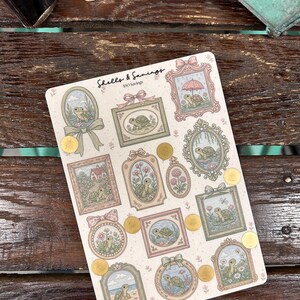 May include: A sticker sheet featuring various framed illustrations of turtles in pastel colors. The sheet includes the text "Shells & Savings" and several gold foil accents. The turtle illustrations are in oval, square, and circular frames.
