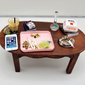 May include: A miniature wooden coffee table with a pink tray, a glass bong, a pack of Marlboro cigarettes, a cell phone, a small bowl with a cigarette, a KFC bucket, and a glass of boba tea.