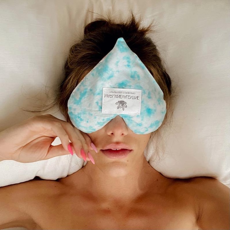 May include: A blue and white tie-dye heart-shaped eye mask with the text "Mindful Moments" and a small leaf design.