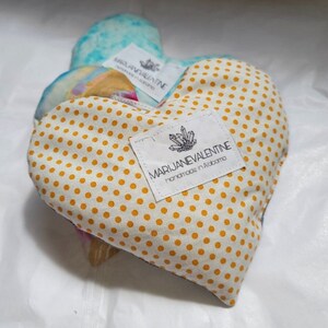 May include: Two heart-shaped fabric pillows with yellow polka dots. The pillow on the right has a white label with the text "MARIJANEVALENTINE handmade in Alabama".