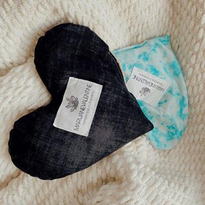 May include: Two heart-shaped fabric pillows with tie-dye patterns. The black pillow has a label that reads "MARIJUANEVALENTINE Handmade in Alabama".