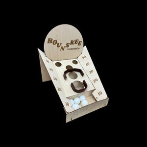 以下が含まれることがあります： 「BOUNSKEE」の文字とウェブサイトのアドレスが上部に印刷された木製ゲーム。ゲームは円形のバックボード、ポイント値のある角度の付いた側面、茶色のハンドルを備えています。いくつかの白いボールがトレイに入っています。