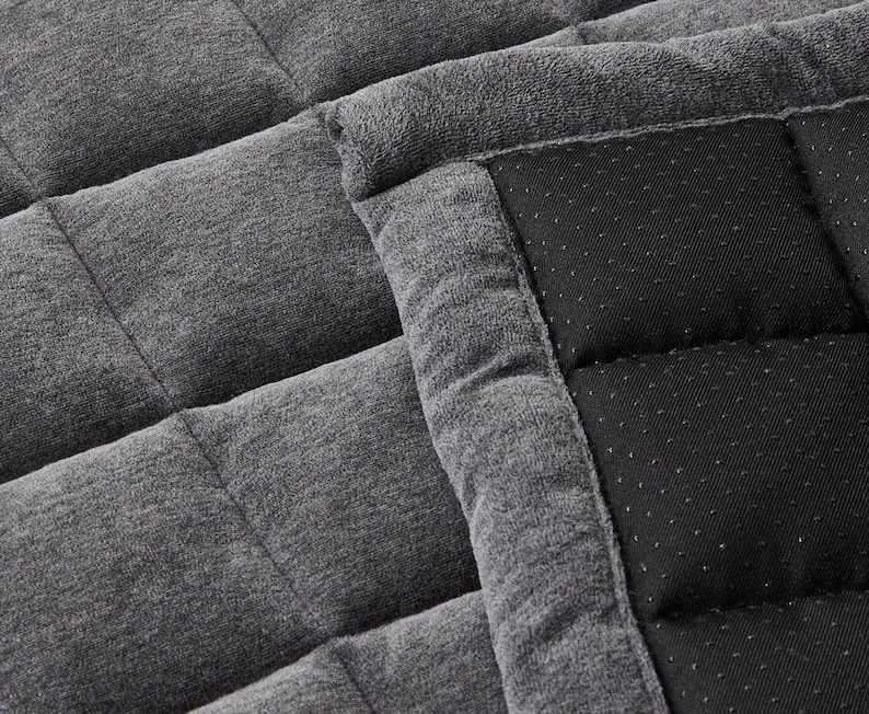 May include: A gray and black quilted throw blanket with a soft, plush texture. The blanket is made of two different fabrics, one with a smooth, woven texture and the other with a soft, fuzzy texture.