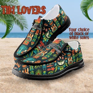 Peut inclure: Paire de chaussures &agrave; enfiler avec un motif color&eacute; sur le th&egrave;me Tiki. Les chaussures pr&eacute;sentent un fond sombre avec des motifs Tiki orange, verts et bleus. Les semelles sont noires, et le texte "Tiki Lovers" est affich&eacute; en haut.