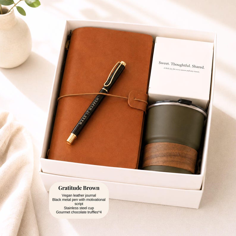 Pu&ograve; includere: Un set regalo in una scatola bianca include un diario in pelle vegana marrone, una penna nera con il testo "MAKE IT HAPPEN", una tazza in acciaio inossidabile e una carta con "Sweet. Thoughtful. Shared."