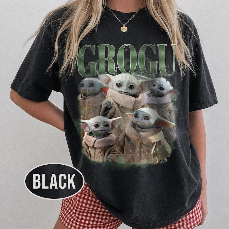 May include: Black t-shirt featuring a graphic of Grogu, also known as Baby Yoda, surrounded by multiple images of himself. The word "GROGU" is printed in green above the images. A black oval with the word "BLACK" is at the bottom.