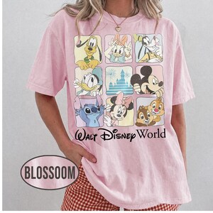 May include: A light pink short-sleeve t-shirt featuring a grid of nine squares with various Disney characters and a castle, including Pluto, Daisy, Goofy, Donald, Mickey, Stitch, Minnie, and Chip and Dale, with the text Walt Disney World below.