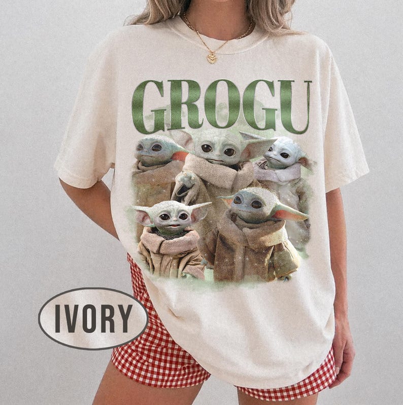 May include: Ivory-colored t-shirt featuring a graphic of Grogu, with the word "GROGU" in green above the image. The graphic shows multiple Grogu characters in various poses. The shirt is a relaxed fit.