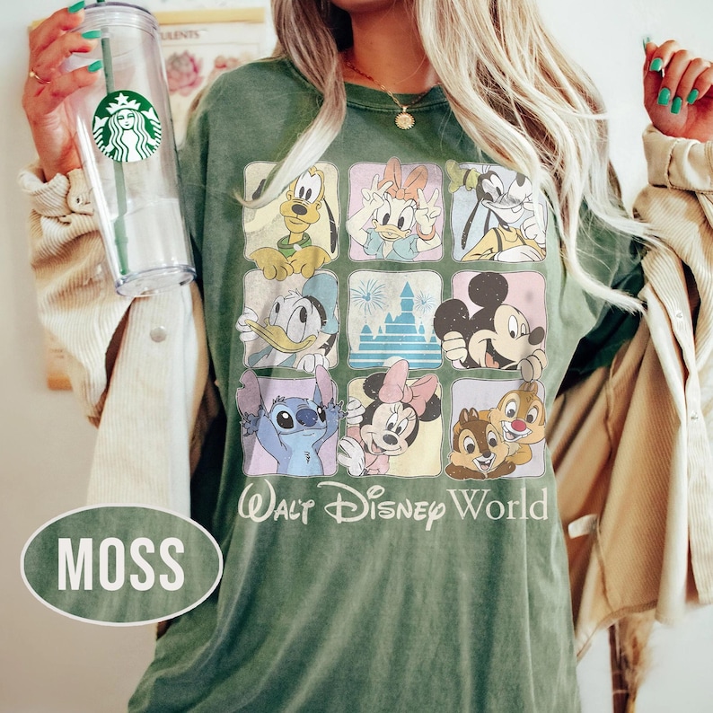 May include: A moss green t-shirt featuring a grid of nine squares with Disney characters including Pluto, Daisy Duck, Goofy, Donald Duck, a castle, Mickey Mouse, Stitch, Minnie Mouse, and Chip and Dale, with the text Walt Disney World.