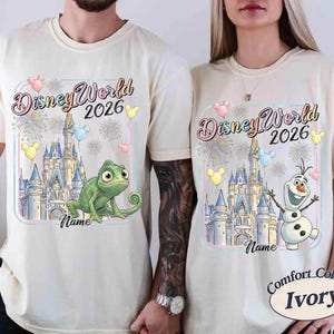 May include: Ivory-colored t-shirts with a Disney World 2026 design. One shirt features a green chameleon, the other Olaf the snowman, both in front of a castle. The design includes balloons and fireworks.