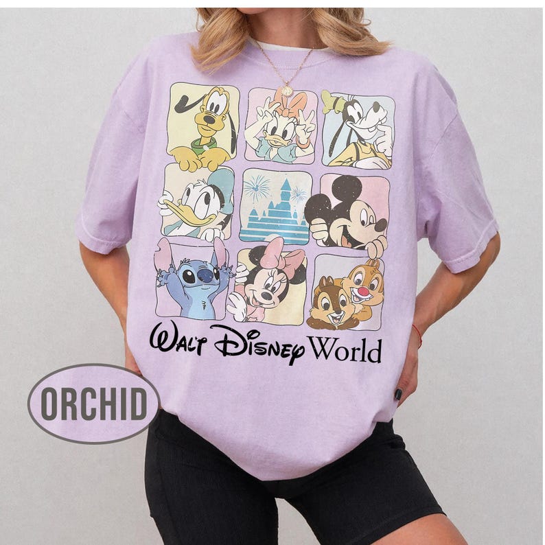 May include: A light purple short-sleeve t-shirt featuring a grid of nine squares with illustrations of Disney characters and a castle. Below the grid, the text Walt Disney World is printed in black. The word ORCHID appears in an oval graphic.