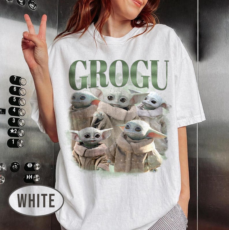 May include: White t-shirt featuring the word "GROGU" in green block letters above a graphic of Grogu, also known as Baby Yoda, from the Star Wars series. The graphic shows multiple images of Grogu.