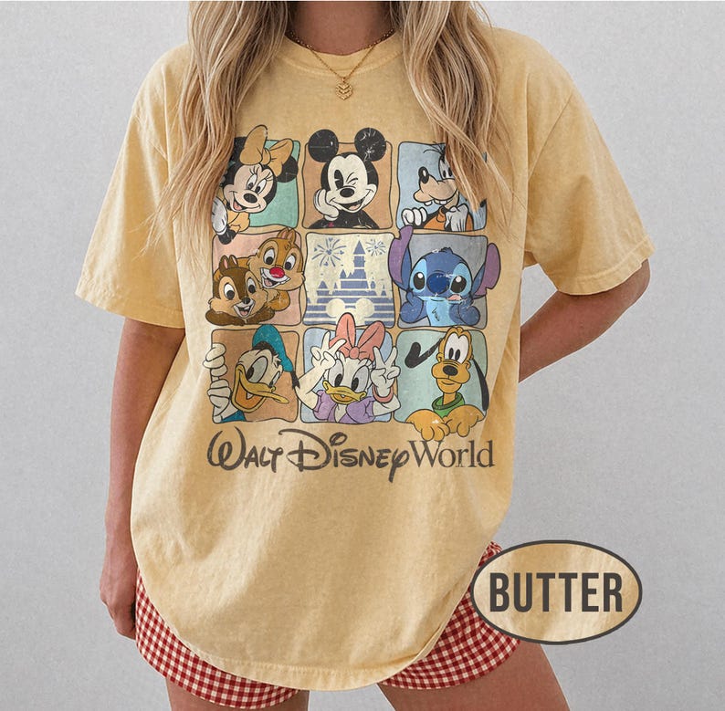 Op de afbeelding: Boterkleurig T-shirt met een raster van Disney-personages, waaronder Mickey Mouse, Minnie Mouse, Donald Duck en Stitch. De woorden "Walt Disney World" staan eronder gedrukt. Het shirt heeft korte mouwen en een relaxte pasvorm.