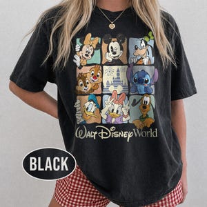 Op de afbeelding: Zwart T-shirt met een raster van Disney-personages, waaronder Mickey en Minnie Mouse, Goofy, Donald en Daisy Duck, Chip en Dale en Stitch. De tekst "Walt Disney World" staat eronder.
