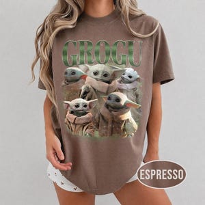 May include: Espresso-colored t-shirt featuring a graphic of Grogu, with the word "GROGU" in green above the image. The image shows multiple Grogu characters. The shirt is a short-sleeved, crew neck style.