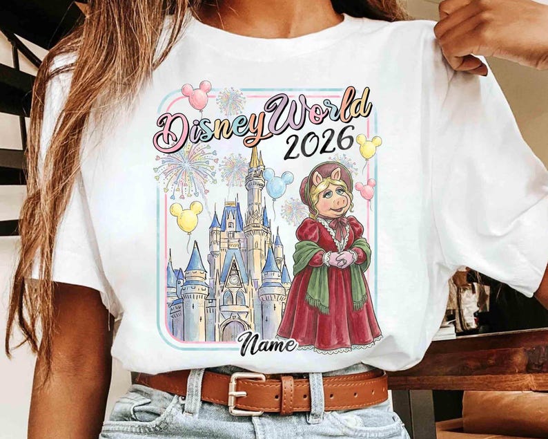 May include: White t-shirt featuring a colorful graphic of Miss Piggy in a red dress, standing in front of Cinderella's castle. The text "Disney World 2026" is above the image, with space for a name below.