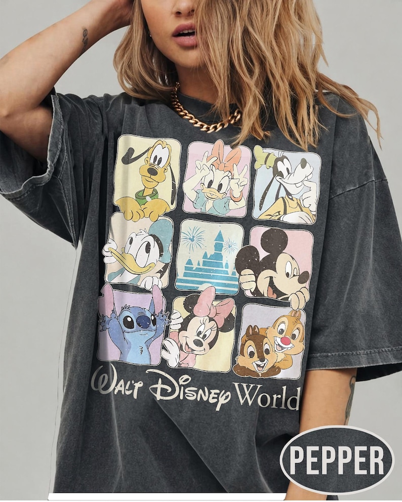 May include: A charcoal gray oversized t-shirt featuring a grid of nine squares with illustrations of Disney characters including Pluto, Daisy Duck, Goofy, Donald Duck, a castle, Mickey Mouse, Stitch, Minnie Mouse, and Chip and Dale, with Walt Disney World text.