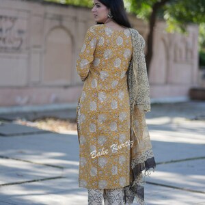 May include: A yellow and white floral print kurta with matching pants and a cream and black dupatta. The kurta has a round neckline and three-quarter sleeves. The pants have a straight leg and the dupatta is a sheer fabric with a black border.