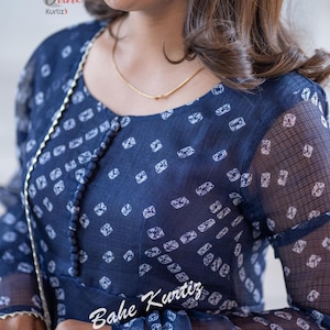May include: A navy blue sheer top with a white geometric print. The top has a round neckline and long sleeves. The text "Bahe Kurtiz" is visible on the sleeve.