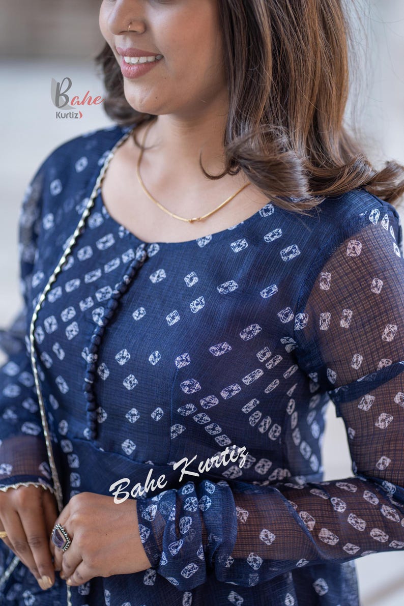 May include: A navy blue sheer top with a white geometric print. The top has a round neckline and long sleeves. The text "Bahe Kurtiz" is visible on the sleeve.