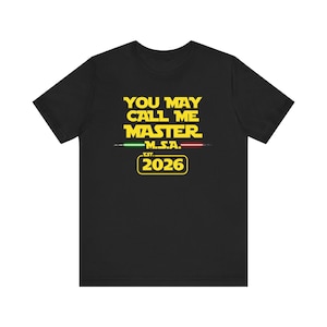 Puede incluir: Camiseta negra con texto amarillo que dice "YOU MAY CALL ME MASTER" encima de "M.S.A." y "EST. 2026". El diseño incluye líneas verdes y rojas y es una parodia de una popular franquicia de ciencia ficción.