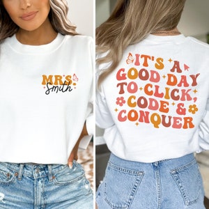 May include: White sweatshirt with a butterfly and the text "MRS. Smith" on the front and the text "IT'S A GOOD DAY TO CLICK, *CODE* & *CONQUER*" on the back.