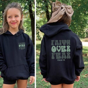 May include: Black hoodie featuring the text "Faith Over Fear" in green lettering on the front and back. The back of the hoodie also includes "Psalm 118". The hoodie has a front pocket and a hood.