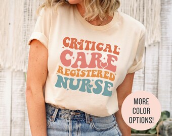 May include: A white t-shirt with the text "CRITICAL CARE REGISTERED NURSE" in a retro font with rainbow colors. The text is surrounded by small stars and hearts.