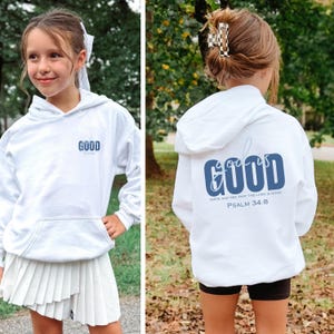 May include: White hoodie with the word "GOOD" in blue on the front and back. The back of the hoodie also features the text "Taste and see that the Lord is good. Psalm 34:8". The hoodie has a front pocket and a hood.