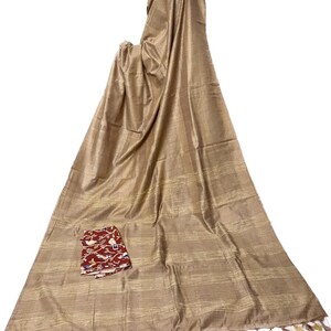 Op de afbeelding: Een beige zijden sari met gouden strepen en een bloemetjesblouse in rood en wit. De sari heeft een franje rand.