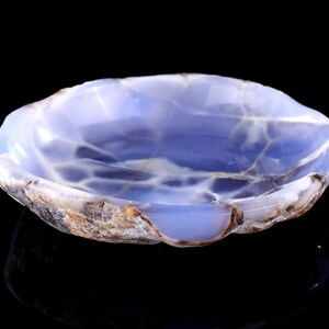 May include: A blue agate bowl with a natural, irregular shape. The bowl has a light blue color with white and brown markings.