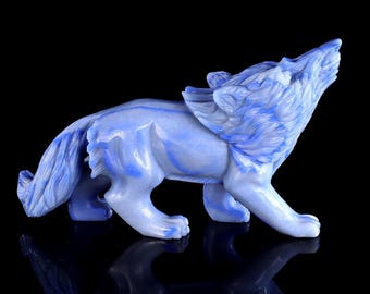May include: A carved stone figurine of a wolf in a howling position. The sculpture features a smooth, polished surface with a marbled appearance, displaying various shades of light blue and darker blue streaks throughout the entire body.