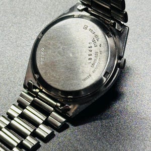 May include: A stainless steel Seiko watch with a silver strap. The watch face is round with the word "SEIKO" printed on it. The back of the watch has the text "WATER RESISTANT" and other markings.