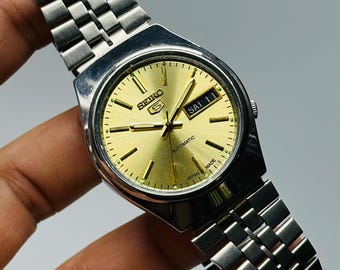 Reloj automático vintage Seiko 5: esfera dorada, caja de acero inoxidable plateada.