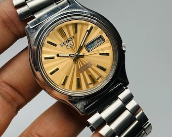 Reloj automático vintage Seiko 5: esfera dorada, acero inoxidable plateado, fabricado en Japón.