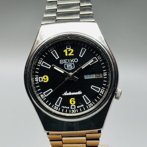 Reloj de pulsera Seiko 5 automático, usado, raro, con esfera negra y caja plateada, calibre n.° 7019, día/fecha, fabricado en Japón.
