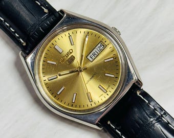 Reloj automático vintage Seiko 5: esfera dorada, caja plateada, día/fecha