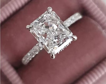 Può includere: Un anello di fidanzamento con diamante taglio radiant e fascia pavé. Il grande diamante rettangolare è incastonato con quattro griffe. L'anello è presentato in un cofanetto di velluto rosa, che ne esalta la brillantezza e il design.