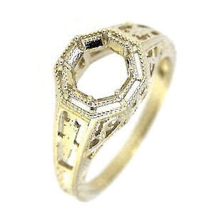 May include: A gold-toned ring with an open, octagonal setting. The ring features intricate filigree detailing along the band and around the setting, showcasing a vintage or antique style. The ring is designed to hold a gemstone.